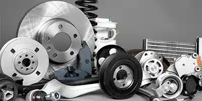 Assorted car parts including brake discs, springs, and gears on a gray surface.