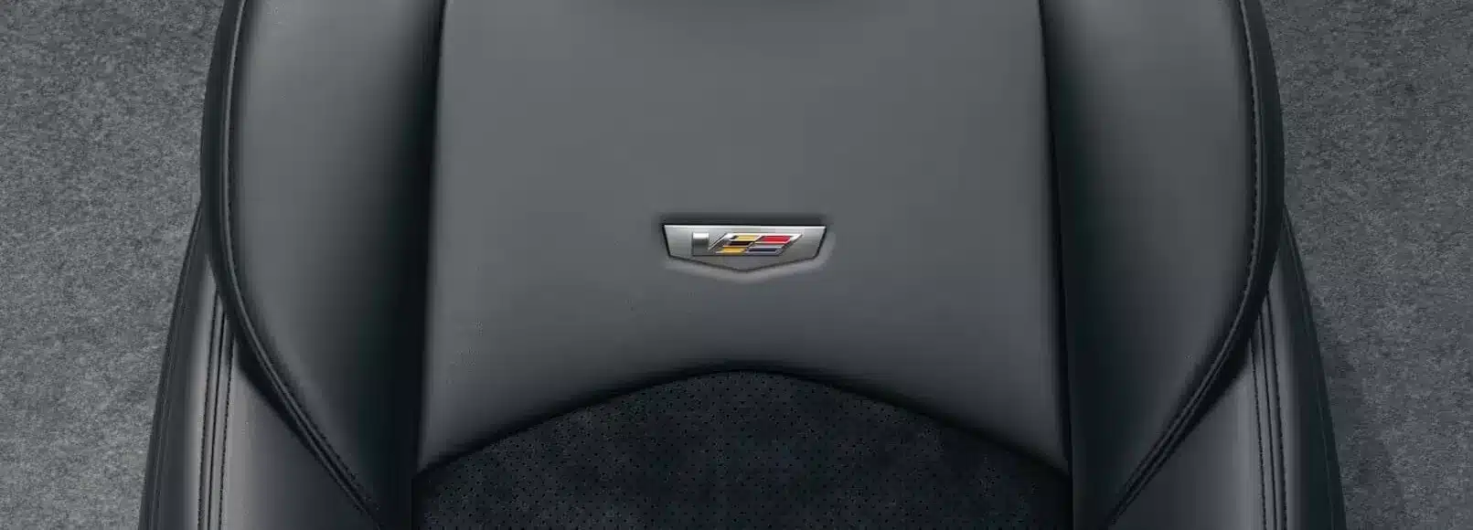 Close-up of a luxurious black leather car seat with an emblem featuring red, yellow, and blue accents.