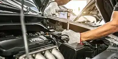 Mechanic using a wrench to repair a car engine, showcasing automotive service and maintenance.