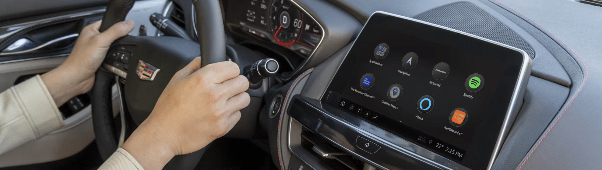 Driver holds steering wheel in a vehicle with a digital dashboard displaying apps like Spotify, Alexa, and Navigation.